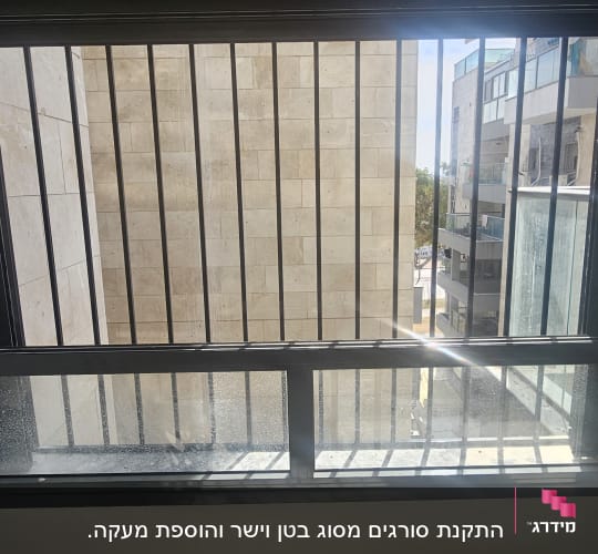 חלון עם סורגים ומסגרת מתכת שחורה